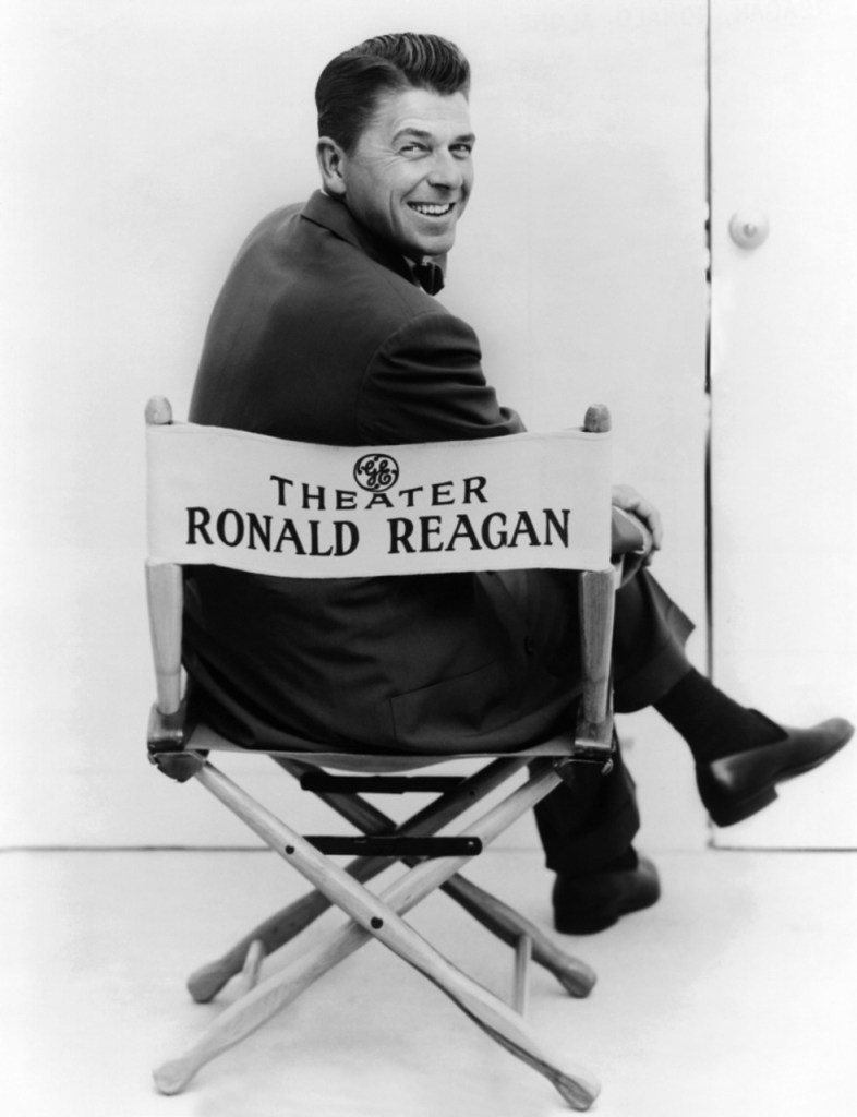 Fotografie publicitara pentru seria de antologie a Teatrului General Electric in care gazda spectacolului, Ronald Reagan, este fotografiata stand pe scaunul regizorului.